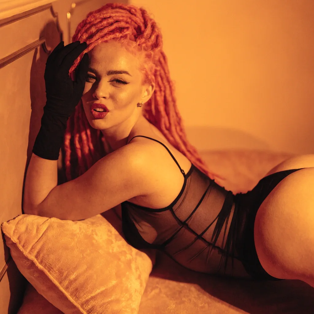 woman with pink locs and gloves in amber light